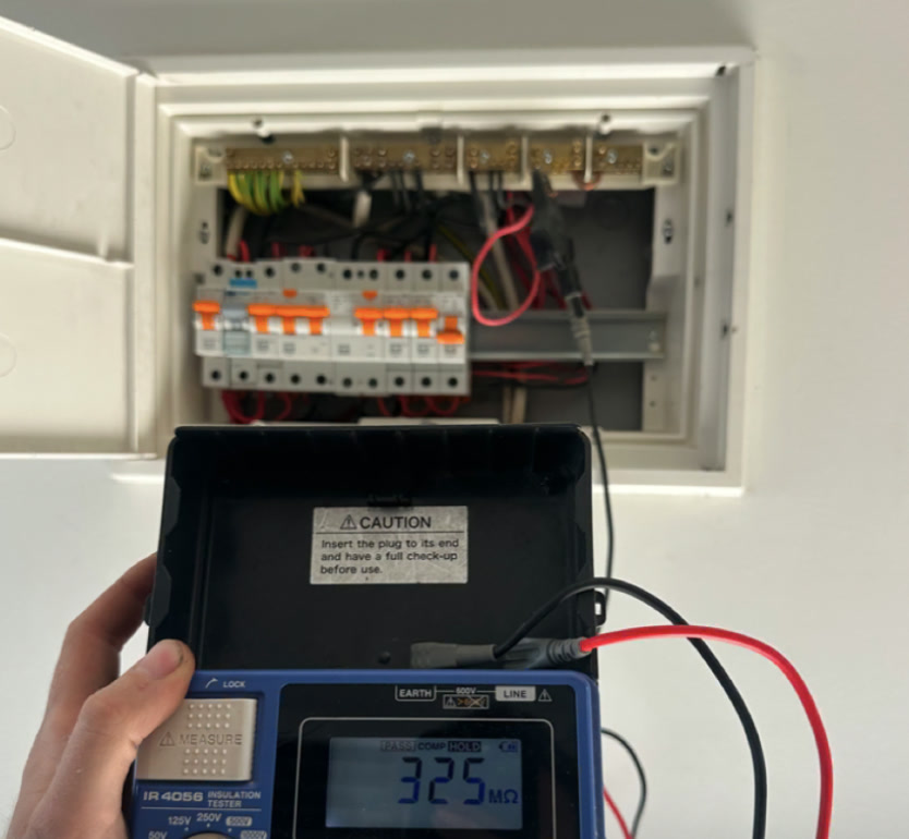 Empowering Melbourne electrician performing Megger insulation resistance testing on a switchboard